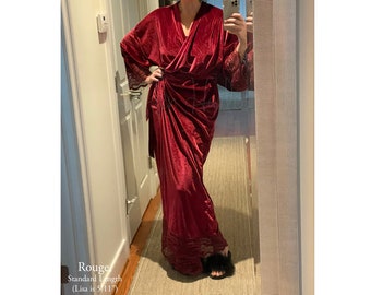 May include: A long, red velvet robe with lace trim at the sleeves and hem. The robe is tied at the waist with a sash. The text "Rouge Standard Length (Lisa is 5'11')" is visible at the bottom of the image.