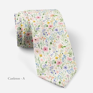 Pode incluir: Uma gravata com fundo creme apresentando um padr&atilde;o floral repetitivo em estilo aguarela de flores silvestres cor-de-rosa, azuis e amarelas, com caules e folhas verdes. O texto "Castleton - A" est&aacute; impresso no canto inferior esquerdo.