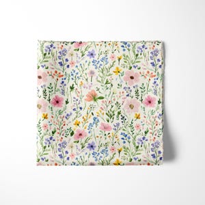 Pode incluir: Uma pe&ccedil;a de tecido quadrada com uma estampa em aquarela de v&aacute;rias flores silvestres em tons de rosa, azul, amarelo e verde sobre um fundo branco off-white. O padr&atilde;o consiste em pequenas flores espalhadas, bot&otilde;es e caules e folhas verdes finas.
