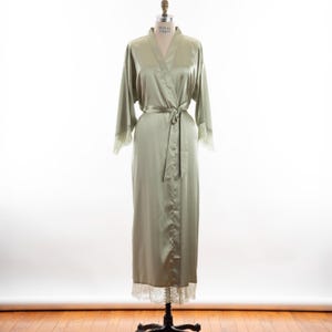May include: A sage green satin robe with lace trim at the sleeves and hem. The robe has a tie belt and a V-neck.