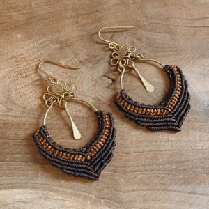 Peut inclure: Une paire de boucles d'oreilles créoles en brun et or avec un motif tissé. Les boucles d'oreilles ont un design délicat et complexe et sont parfaites pour ajouter une touche de style bohème à n'importe quelle tenue.