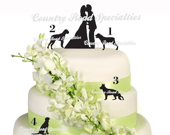 May include: A three-tiered wedding cake decorated with white flowers and green ribbon. The top tier features a silhouette of a bride and groom kissing, with a dog silhouette on each side. The second tier has a dog silhouette and the third tier has a dog silhouette. The cake is decorated with the text "Country Road Specialties" on each tier.