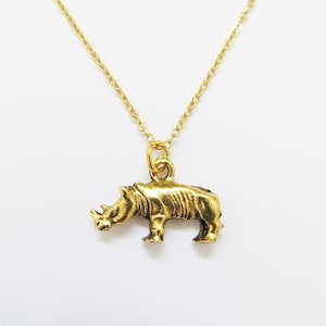 Peut inclure: Un collier doré avec un pendentif rhinocéros. Le pendentif rhinocéros présente une peau texturée et une petite corne. La chaîne est délicate et dorée, créant un bijou simple mais accrocheur.