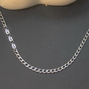 May include: A silver chain necklace with a series of letter 'B' charms.
