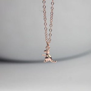 May include: A rose gold necklace with a small dinosaur pendant.