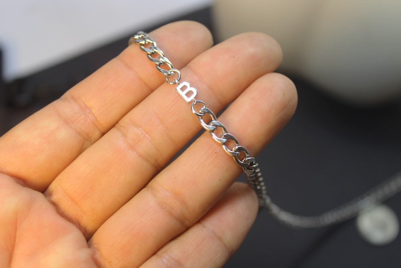 May include: A silver chain necklace with a silver charm that has the letter "B" on it.