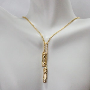 Puede incluir: Un collar de cadena dorada con dos colgantes de bailarina dorada. El collar es ajustable y se puede usar en diferentes longitudes.