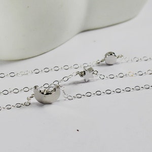 May include: Three silver chains with a crescent moon and star charm. The chains are linked together and have a delicate, feminine look.