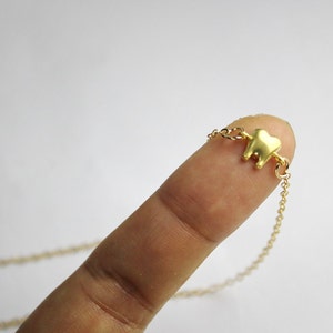 May include: A gold chain necklace with a small gold tooth charm.