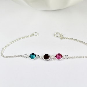 Peut inclure: Un bracelet en chaîne argent avec trois pierres rondes : turquoise, rouge et rose.