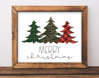 May include: A framed print with three Christmas trees in different plaid patterns. The trees are green, gold, and red. The text "Merry Christmas" is written below the trees.