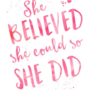 May include: A pink watercolour print featuring the quote "She BELIEVED she could so SHE DID" in a flowing script. The design includes pink paint splatters and the text "Joyful Art Designs".