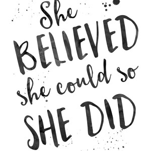 May include: Monochrome art print featuring the motivational quote "She Believed she could so SHE DID" in a handwritten font. The design includes ink splatters and the text "Joyful Art Designs".
