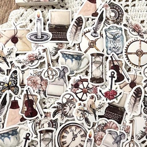 May include: A sheet of vintage-style stickers featuring various images, including clocks, birds, feathers, an hourglass, a typewriter, a candle, a compass, a violin, a butterfly, and a teacup. The stickers are printed on white paper with a light brown background.