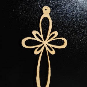 May include: A wooden cutout of a stylized flower with a hole at the top for hanging. The flower is a light brown color and has a simple, elegant design.