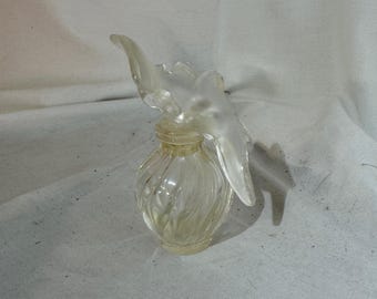 May include: A clear glass perfume bottle with a textured design and a decorative flower-shaped stopper.