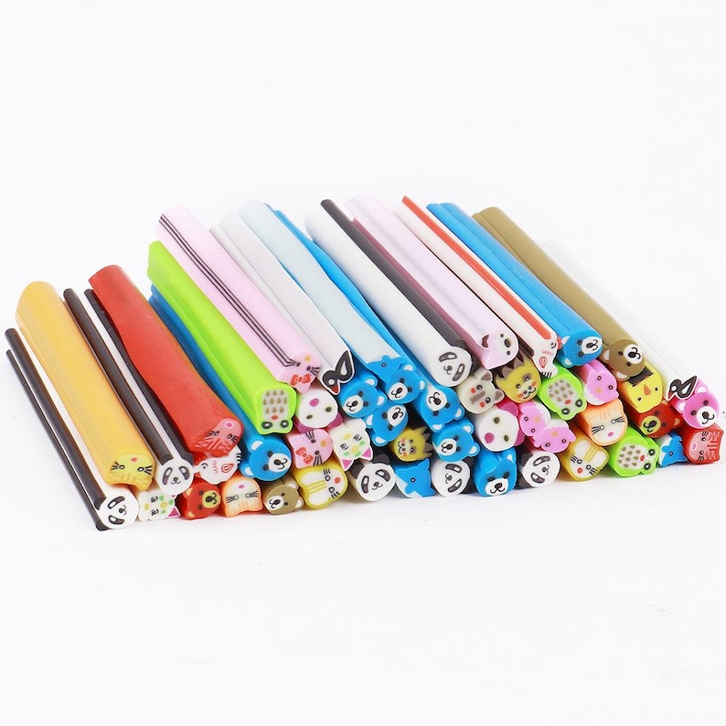 May include: A collection of colorful polymer clay canes, each featuring a different animal face design. The canes are in various colors, including yellow, red, blue, and green, and are stacked together.