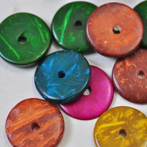 May include: Assortment of colourful round wooden beads with a hole in the centre. The beads are painted with different patterns and colours, including green, blue, red, orange, and yellow.