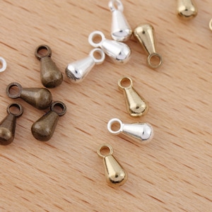 May include: Assortment of small teardrop-shaped metal charms in silver, gold, and bronze finishes. The charms have a small loop at the top for attaching to jewelry or other crafts.