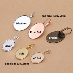 Puede incluir: Una variedad de bases de pendientes ovaladas en acabados metálicos, incluyendo Rodio, Plata, Oro Rosa, Oro, Oro KC y Bronce. La imagen muestra dos tamaños, con tamaños de almohadilla de 18x25mm y 13x18mm.