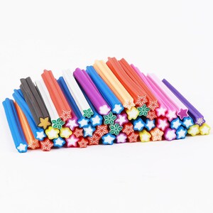 May include: A collection of colorful polymer clay sticks, each with a star-shaped design on the ends. The sticks are in various colors, including blue, black, red, and pink. The star designs are white, yellow, and green.