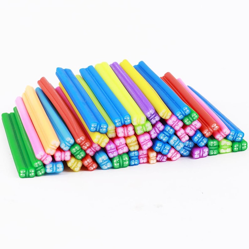 May include: A pile of colorful polymer clay sticks in various shades of green, pink, yellow, red, blue, and purple. The sticks are arranged in a random pattern, with the ends of the sticks showing a floral design.