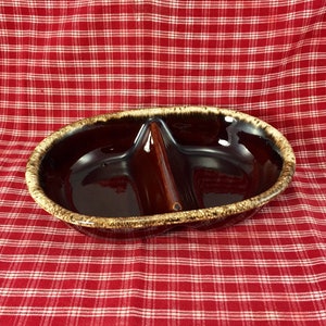 May include: A brown and tan glazed ceramic divided serving dish with a center divider. The dish is oval shaped and has a glossy finish.