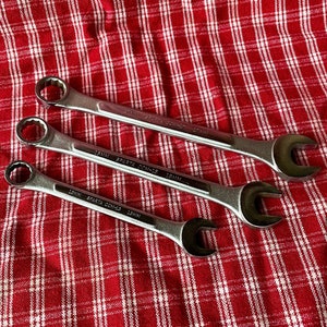 May include: Three silver wrenches with black handles on a red and white checkered surface. The wrenches are labeled "SPARTA COM-15 15MM".
