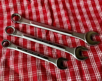 May include: Three silver wrenches with black handles on a red and white checkered surface. The wrenches are labeled "SPARTA COM-15 15MM".