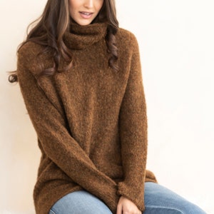 May include: A brown turtleneck sweater with a fuzzy texture. The sweater is worn with blue jeans.