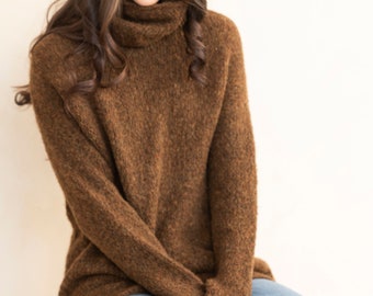May include: A brown turtleneck sweater with a fuzzy texture. The sweater is worn with blue jeans.