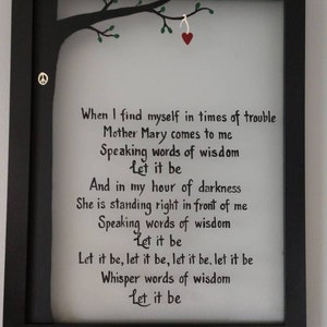 Puede incluir: Una impresión enmarcada con un marco negro y un fondo blanco. La impresión presenta un árbol negro con hojas verdes y un corazón rojo colgando de una rama. El texto en la impresión dice: "When I find myself in times of trouble Mother Mary comes to me Speaking words of wisdom Let it be And in my hour of darkness She is standing right in front of me Speaking words of wisdom Let it be Let it be, let it be, let it be, let it be Whisper words of wisdom Let it be".