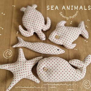 May include: A sewing pattern for making five plush sea animal toys: a turtle, a whale, a fish, a starfish, and a shark. The toys are made of white fabric with red polka dots.