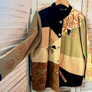Op de afbeelding: Een veelkleurig patchworkjack met een mandarijnsluiting en knoopsluiting. Het jack heeft een verscheidenheid aan texturen en patronen, waaronder swirls, geometrische vormen en geborduurde details.