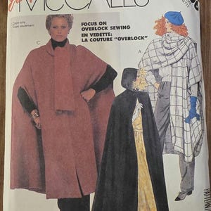 May include: McCall's sewing pattern envelope featuring illustrations of capes. The envelope has the number 2266 and text that reads "Focus on Overlock Sewing". The main color is white with illustrations of capes in black, red, and white.