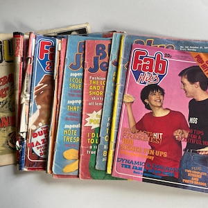May include: A collection of vintage magazines with vibrant covers. Titles include "Fab Hits," "Fabulous 2," and "Buz." The magazines display images of people, text, and graphics. The covers show signs of age and use.