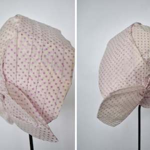 Può includere: Un cappello in stile vintage color crema con un motivo a piccoli pois viola distanziati. Il cappello ha una corona a pieghe e un'ampia tesa a balze. Il tessuto sembra leggero e il cappello è esposto su un supporto nero.