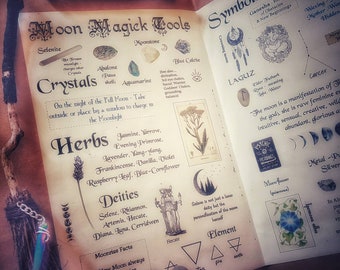 May include: An open book with the title "Moon Magick Tools" displays information on crystals, herbs, and deities. A witch's broom and a vial of crystals are on the left. The book also features symbols and moon phases.