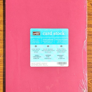 May include: A package of pink card stock labeled "Purely Pomegranate." The package contains 24 sheets of 8.5" x 11" card stock. The label also indicates the paper is acid-free and lignin-free.