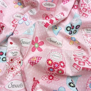 May include: Pink fabric with a repeating pattern of jars filled with sweets, lollipops, liquorice, bubble gum, and chocolate. The jars are decorated with colourful buttons and flowers. The fabric also features the words "Sweet Shop", "Lollipops", "Candy", "Bubble Gum", "Liquorice", "Chocolate", "Sweets", and "Sweet".