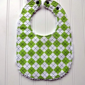 May include: Green and white checkered baby bib with a white frayed edge and two black snap closures.