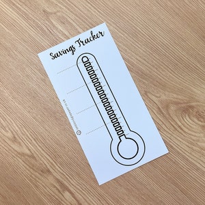 Puede incluir: Un rastreador de ahorros imprimible en forma de termómetro. El rastreador tiene líneas para registrar objetivos de ahorro y un termómetro para realizar un seguimiento del progreso.