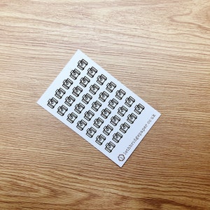 May include: A sheet of white paper with black camera icons printed on it. The sheet is folded in half and the text "leithbridgepaper.co.uk" is printed on the bottom right corner.