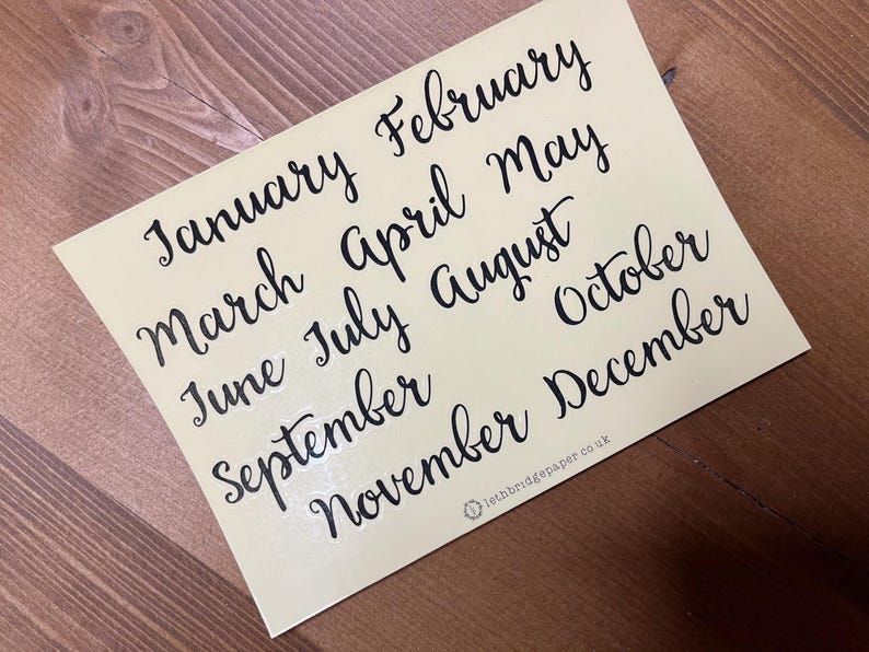 May include: A cream-coloured sticker displaying the months of the year in stylish black cursive lettering. The months are arranged in a neat layout, with the text "lethbridgepaper.co.uk" at the bottom.