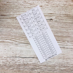 K&ouml;nnte beinhalten: Ein Blatt wei&szlig;es Papier mit 12 monatlichen Kalenderausklebern. Jeder Aufkleber hat einen Monatsnamen und die Wochentage abgek&uuml;rzt als M, T, W, T, F, S, S. Die Aufkleber sind f&uuml;r die Verwendung in einem Planer oder Tagebuch gedacht.