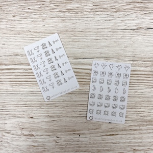 May include: Two sheets of stickers with black and white illustrations. The first sheet features icons related to hair care, such as scissors, hair dryers, and bottles of hair products. The second sheet features icons related to travel, such as airplanes, passports, and luggage. Both sheets have the text "lethbridgepaper.co.uk" printed on them.