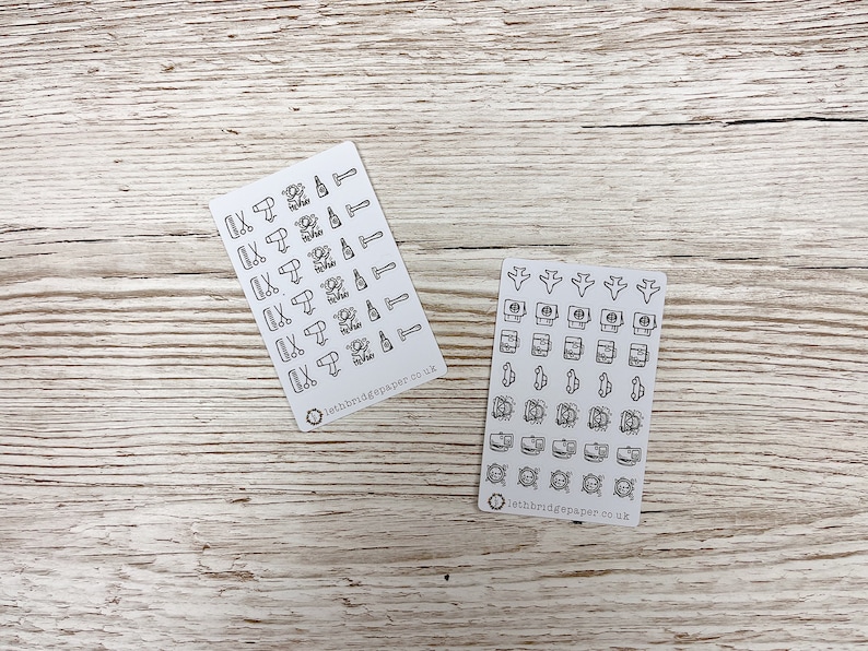 May include: Two sheets of stickers with black and white illustrations. The first sheet features icons related to hair care, such as scissors, hair dryers, and bottles of hair products. The second sheet features icons related to travel, such as airplanes, passports, and luggage. Both sheets have the text "lethbridgepaper.co.uk" printed on them.