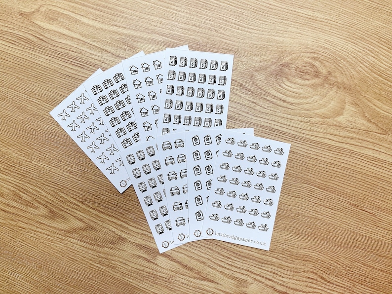May include: A set of six sheets of stickers featuring various travel-themed icons. The icons include aeroplanes, cameras, houses, cars, washing machines, and boats. The stickers are printed on white paper and have a black outline.