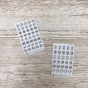 May include: Two sheets of white sticker paper with black outline icons. The first sheet has icons of various objects, including a camera, a cup of coffee, a book, and a plant. The second sheet has icons of various mail-related objects, including envelopes, stamps, and mailboxes. Both sheets have the text "lethbridgepaper.co.uk" at the bottom.