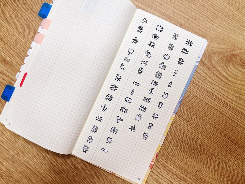 May include: A page from a notebook with a grid pattern. The page is filled with black and white icons representing various activities, objects, and concepts. Some of the icons include a pizza slice, a camera, a house, a plane, a coffee cup, a tooth, and a pair of glasses.